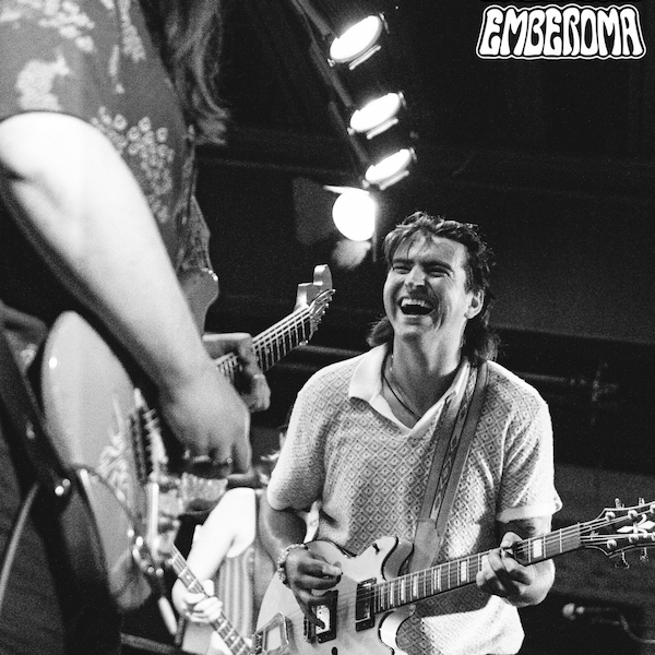 Three people playing an electric guitar on a stage.